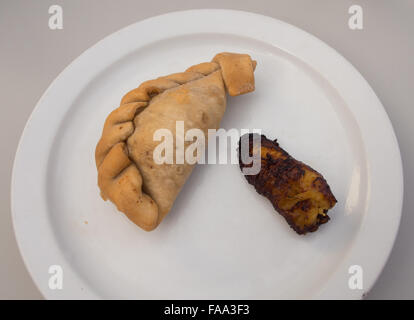 Weißen Teller mit Empanada und gebratenen Kochbananen Stockfoto