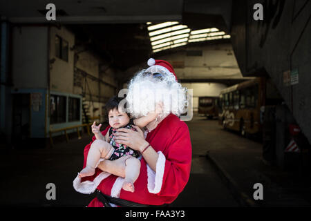 Buenos Aires, Argentinien. 24. Dezember 2015. Cristian Gabriel Tamasi (R), Treiber von der Buslinie 39, posiert mit einem Mädchen vor Beginn seiner üblichen Route als Santa Claus, in Buenos Aires, Hauptstadt von Argentinien, am 24. Dezember 2015 gekleidet. Cristian, 22-Year-Old, wurde ein Busfahrer für ein Jahr und eine Hälfte. Er beschloss, gehen zur Arbeit verkleidet als Weihnachtsmann schenken Freude Passagiere und die Weihnachtsstimmung zu verbreiten. © Martin Zabala/Xinhua/Alamy Live-Nachrichten Stockfoto