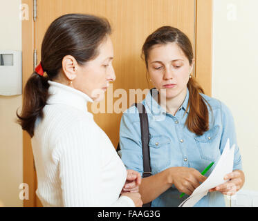 Weibliche Sammler wird versuchen, die Schulden von Reife Frau im Hause Tür Stockfoto