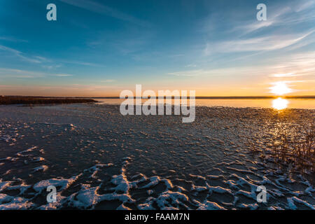 Die Sonne geht am Horizont auf der Winter-Küste, von Wasser und Eis reflektiert wird. Stockfoto