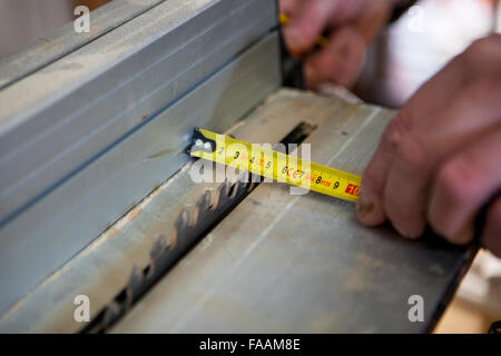 Tischler mit Türpfosten mit elektrischen Kreissäge zu arbeiten. Er misst den Schnittbereich Stockfoto