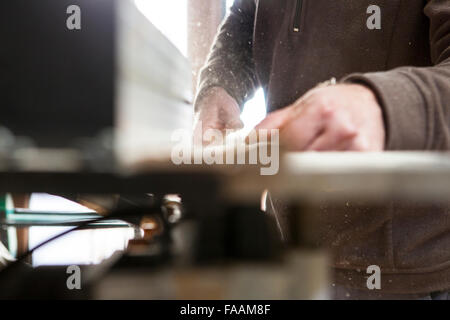 Tischler arbeiten mit Türstöcken elektrische Kreissäge Tabelle verwenden. Sägemehl-Partikel sind in der Luft sichtbar Stockfoto