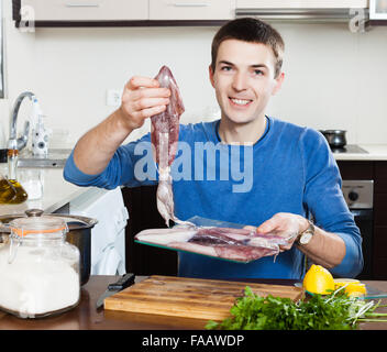 Hübscher Kerl hält roher Tintenfisch in Küche zu Hause Stockfoto