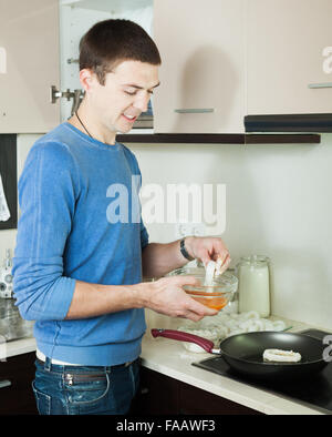 Mann Kochen Tintenfischringe in butter Stockfoto