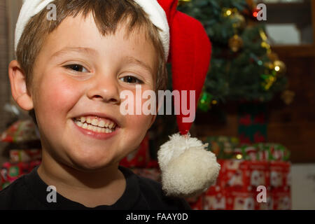 Fröhlicher Junge vor Weihnachten Baum mit Weihnachtsmütze. Stockfoto