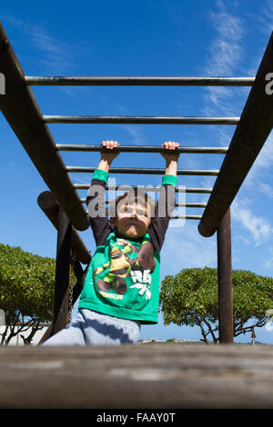 Junge von Klettergerüst auf Klettergerüst hängen. Stockfoto