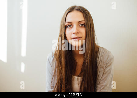 Einsames Mädchen sitzt hinter Weihnachtsbaum mit präsentiert Stockfoto