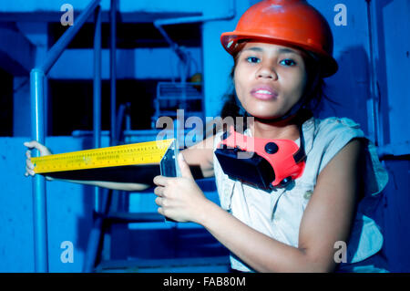 Junge attraktive Asiatin in Schutzhelm auf einer Baustelle Stockfoto