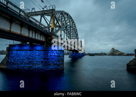 Eisenbahn Brücke über den Fluss Daugava in Riga. Newman-Riga-Bibliothek (Latvijas Nacionālā Bibliotēka) im Vordergrund. Stockfoto