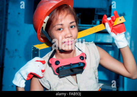 Junge attraktive Asiatin in Schutzhelm auf einer Baustelle Stockfoto