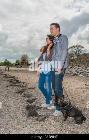 Paar, 25-30 Jahren, am Strand mit Hund Stockfoto