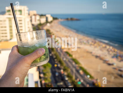 Eine köstliche Kiwi Caipirinha Drink mit Blick auf den berühmten Strand von Ipanema in Rio De Janeiro, Brasilien Stockfoto