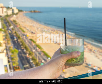 Eine köstliche Kiwi Caipirinha Drink mit Blick auf den berühmten Strand von Ipanema in Rio De Janeiro, Brasilien Stockfoto