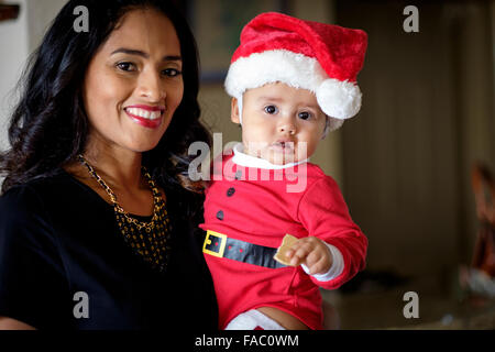 Close up Portrait of hispanic Frau mit ihrem Baby-jungen, in Essen einen Cookie Weihnachts-Outfit gekleidet Stockfoto