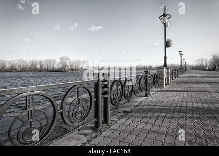 Gehweg entlang des Dnepr Flusses im Stadtteil Obolon Kiew, Ukraine. Weiche Sonne bei einem kalten Wintermorgen. Stockfoto