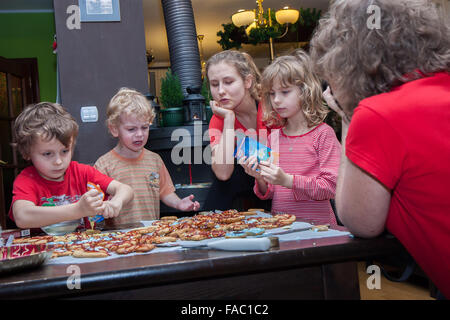 Vier Kinder, festliche Dekoration Ingwer-Kekse mit Zuckerguss und einer Frau, die sie fotografieren... Stockfoto