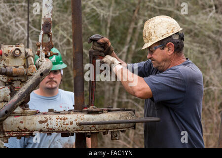 Ölarbeiter Waschbecken Rohre mit Hilfe einer Derrick für Rohöl in Evangeline, Louisiana zu bohren. Die Ölfelder wurden die ersten Brunnen in Louisiana. Stockfoto