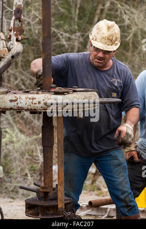 Ölarbeiter Waschbecken Rohre mit Hilfe einer Derrick für Rohöl in Evangeline, Louisiana zu bohren. Die Ölfelder wurden die ersten Brunnen in Louisiana. Stockfoto