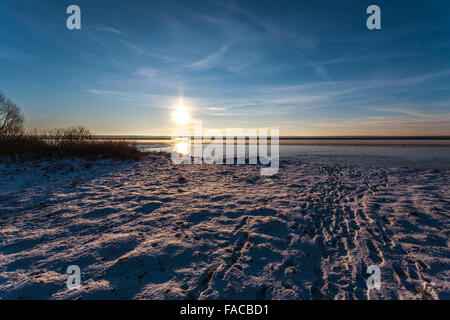Die Sonne geht am Horizont auf der Winter-Küste, von Wasser, Eis und Schnee reflektiert wird. Stockfoto
