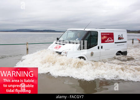 Eine Autofahrer fährt durch Hochwasser auf der Straße bei Storth an der Mündung der Kent in Cumbria, UK, während des Sturms Januar 2014 Stockfoto