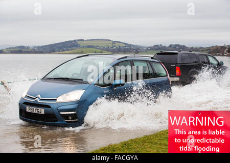 Eine Autofahrer fährt durch Hochwasser auf der Straße bei Storth an der Mündung der Kent in Cumbria, UK, während des Sturms Januar 2014 Stockfoto