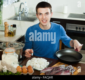 lächelnder Mann Kochen Tintenfisch Ringe im Teig Stockfoto