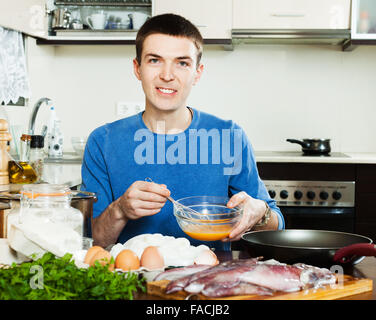 Glücklicher Kerl Braten Calamari Ringe in Teig in Küche Stockfoto