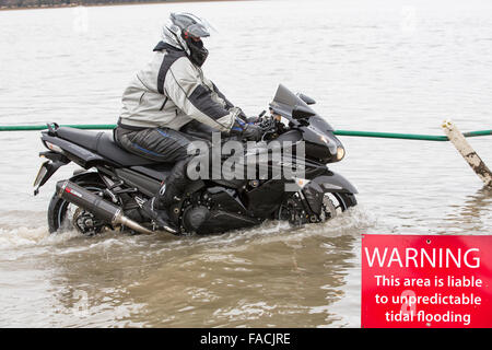 Biker Reisen durch Hochwasser auf der Straße bei Storth an der Mündung der Kent in Cumbria, UK, während die Sturmflut Januar 2014 Stockfoto