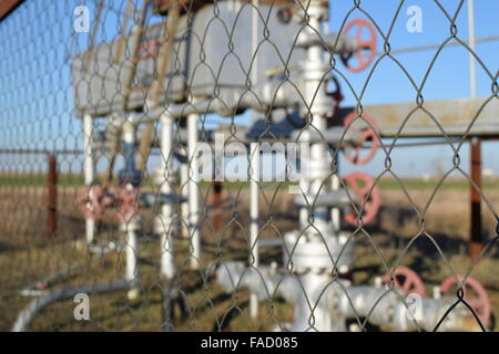 Das Maschendrahtgeflecht-Raster in der Nähe einer Ölquelle. Absperrventile und Werkstattausrüstung. Stockfoto