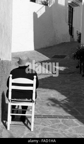 Rückansicht der spanische Dame saß auf einem Stuhl vor ihrem Haus in dem Dorf Totalan, Málaga, Südspanien. Stockfoto