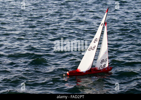 Funksteueryacht segelt auf einem Model Boating Lake. Die International One Meter (IOM) Regatta beliebte RC-Rennyachten, 2-Funktionen-Steuerung und 3 ein-​design-Rigs. Mit drei Segelrigs; Radio Controlled Yachting, Wettbewerb auf Southport, Marine Lake, Merseyside, VEREINIGTES KÖNIGREICH Stockfoto