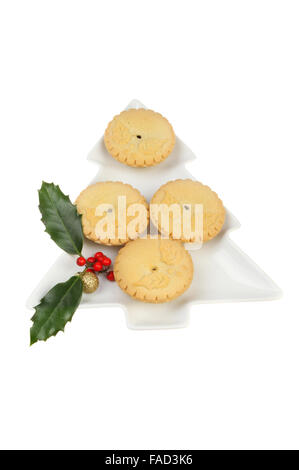 Mince Pies auf einem Weihnachtsbaum geformte Platte, dekoriert mit Holly und eine Christbaumkugel isoliert gegen weiß Stockfoto