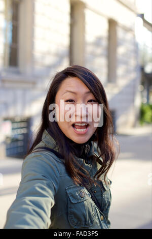 Junge asiatische Frau zieht den Betrachter zu ihr. Stockfoto