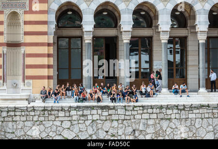 Leute sitzen auf der Treppe des Vijecnica Gebäudes, ehemalige Rathaus und Nationalbibliothek in Sarajevo, Bosnien und Herzegowina Stockfoto
