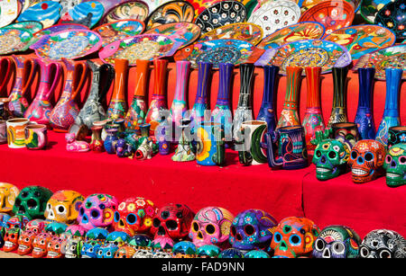 Traditionelle mexikanische bunten Keramik einschließlich Zucker Schädel, auf den Verkauf mit einer roten Tischdecke in Yucatan, Mexiko. Stockfoto