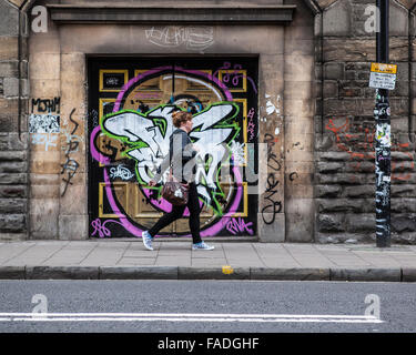 Frau zu Fuß vorbei an Straßenkunst Graffiti in Bristol Stockfoto