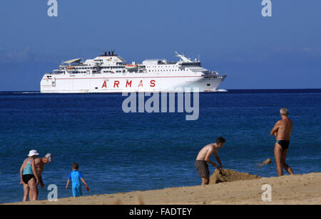 Touristen genießen das sommerliche Wetter am Strand in der Nähe von Morro Jable auf der Kanarischen Insel Fuerteventura, Spanien, 13. Oktober 2015. Unterdessen fährt eine Fähre der Reederei Naviera Armas von im Hintergrund. Foto: Peter Zimmermann - kein Draht-Dienst- Stockfoto