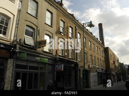 Sonnenschutz Schrägansicht Backsteinbauten mit Geschäften, Ostseite Brick Lane, Pedley Straße alte Truman Brauerei Schornstein, London, UK Stockfoto