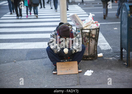 Müde Obdachloser betteln auf der Straße entlang der 5th Avenue in New York City. Stockfoto