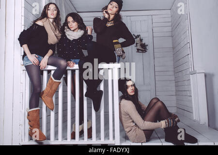 Vier stilvolle Modelle posieren auf dem Zaun sitzen Stockfoto