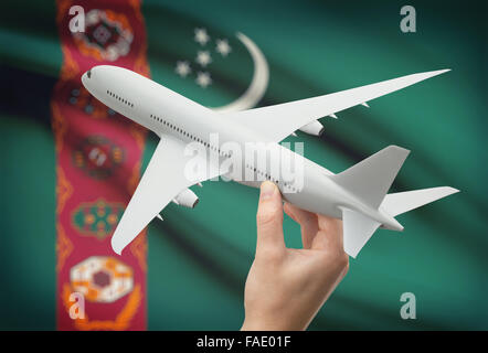 Flugzeug in der Hand mit Nationalflagge auf Hintergrund - Turkmenistan Stockfoto