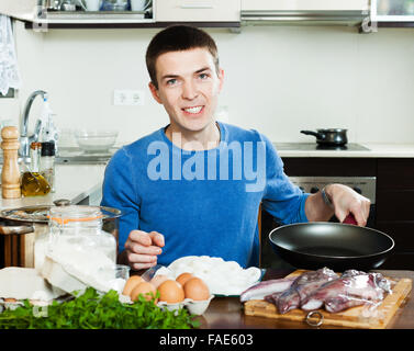 Glücklicher Mann Braten Tintenfischringe zu Hause Stockfoto