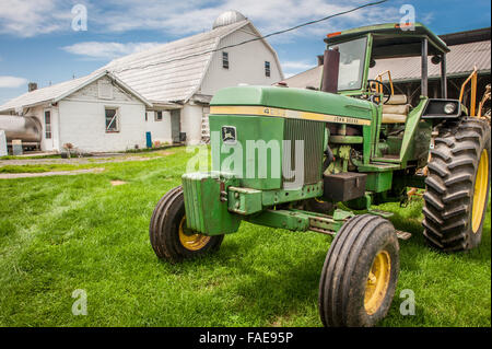 John Deere Traktor parkte vor einer weißen Scheune Stockfoto