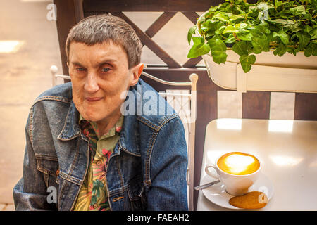 Ein behinderter Mann sitzt in einem Straßencafé. Stockfoto