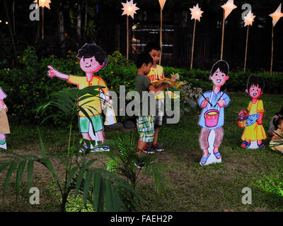 Manila, Philippinen. 27. Dezember 2015. Zwei Jungen spielen neben Karikaturen von Kindern Staatsbahn eine caroling Aktivität. © Josefiel Rivera/Pacific Press/Alamy Live-Nachrichten Stockfoto