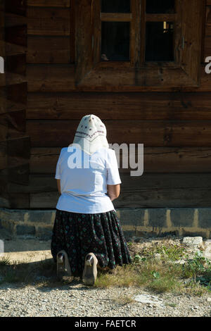 Frau kniend im Gebet auf dem Rasen vor der Kirche Stockfoto