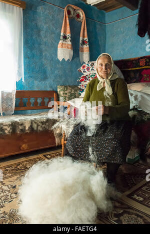 ältere Frau beim Spinnen der Wolle bei ihr zu Hause Stockfoto