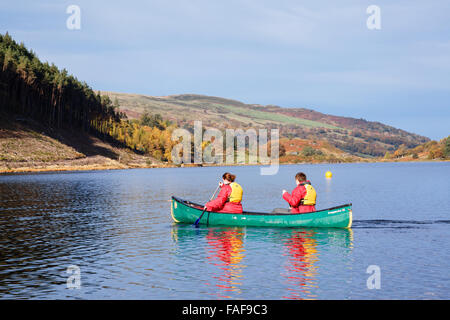 Zwei junge Leute Schwimmwesten Paddeln ein Kanadier Kanu auf Llyn Geirionydd See an einem sonnigen Tag im Herbst in Snowdonia National Park. Wales UK Stockfoto