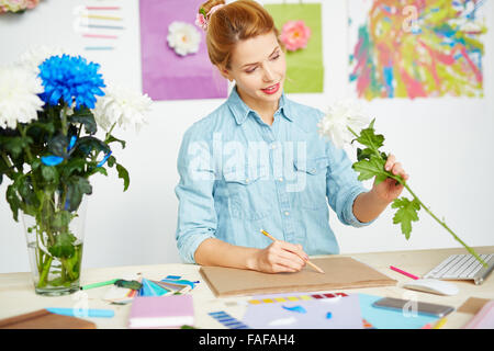 Junge Frau, die Zeichnung einer Blume in ihrem album Stockfoto