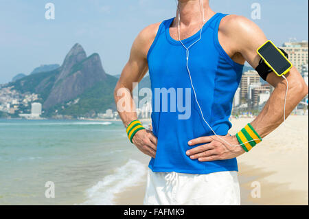 Sportler, die Handy-Technologie Armbinde tragen steht motivierende Musik im Freien auf Ipanema Strand Rio de Janeiro Stockfoto